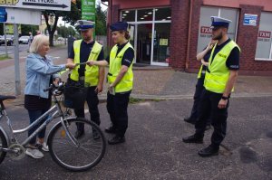 policjanci rozmawiają z rowerzystką, w tle ulica i zabudowania