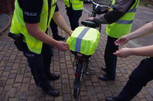 odblaskowy pokrowiec na rowerze, w tle policjanci