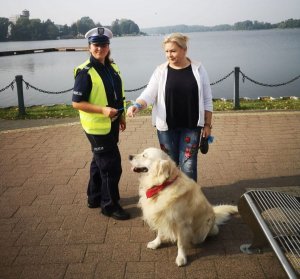 policjantka wręcza odblask kobiecie, w tle jezioro