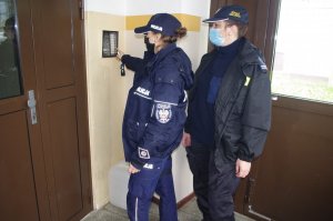 policjantka i strażniczka gminna przy domofonie  w tle ściana klatki schodowej