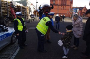 policjantka wręcza przechodniom niespodziankę w tle żubrzyk i ulica