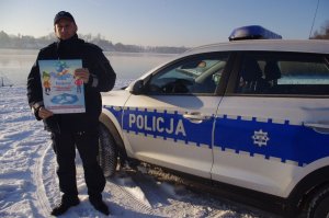 policjant z plakatem  w tle jezioro