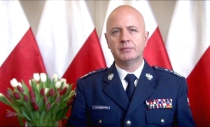 Komendant Główny Policji w tle 3 flagi Polski obok kwity w wazonie