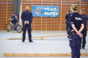 policjanci oceniają test sprawnościowy uczestnika w tle hala