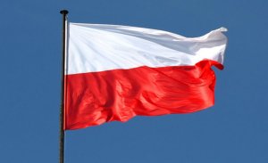 powiewająca flaga Polski na tle chmur