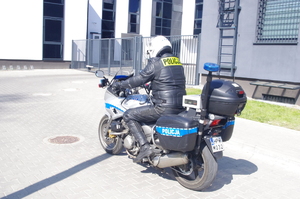 policjant na motocyklu w tle zabudowania