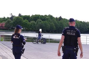 policjanci rozmawiają z rowerzystą, w tle promenada jeziora