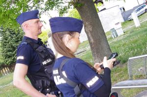 policjanci dokonują sprawdzenia osoby, w tle zieleń drzew