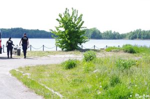 policjanci patrolują teren promenady jeziora w tle jezioro