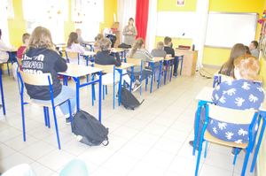 uczniowie w szkolnych ławkach w tle prowadzący spotkanie