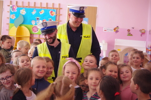 policjanci w białych czapkach otoczeni przez dzieci w tle sala