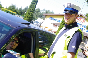 policjant rozmawia z kierowcą w tle zabudowania