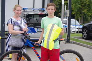 kobieta z synem stoją przy rowerze, w tle radiowóz