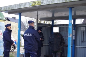 policjanci legitymują osoby w tle przystanek autobusowy