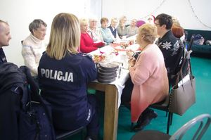 policjanci na spotkaniu z Mikołajem dla seniorów w tle pomieszczenie i choinka