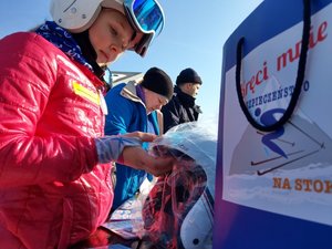 młodzi ludzie w strojach narciarskich w tle torba z hasłem kampani