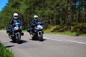 policjanci na motocyklach w tle las i droga