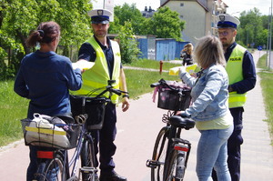 policjanci i rowerzyści w tle ulica i zabudowania