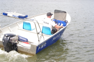 policjant na policyjnej łodzi motorowej w tle jezioro