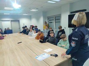spotkanie policjantki z wolontariuszami  w tle sala i ekran z logo WOŚP