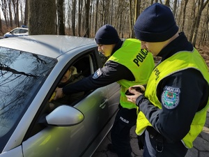 policjanci częstują słodyczami kierującą w tle las