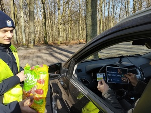 policjanci częstują kierującą słodyczami w tle las