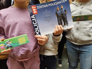 uczniowie trzymają w rękach książkę o tematyce pracy policjanta