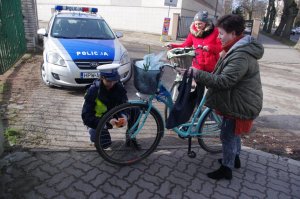 Policjantka zakłada odblaski na wózek dziecięcy w tel radiowóz