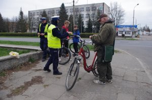 spotkanie policjantów z rowerzystami na tle słupa z ogłoszeniami