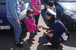 policjantka podaje rękę na powitanie, kucając przy dzieciach