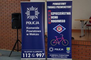 banery: jeden z napisem KPP Wałcz  i logo Policji oraz tel. alarmowy służb, drugi reklamujący Turniej z napisem BRD, na tle banera rower