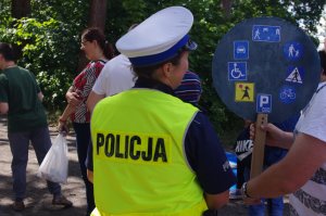 policjantka stoi obok osoby trzymającej baner ze znakami drogowymi