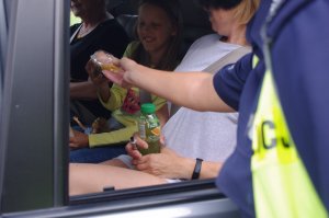 policjantka wręczyła dziecku maskotkę, dziecko siedzi w aucie
