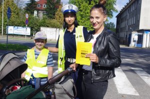 kobieta z wózkiem dziecięcym trzyma dyplom od policjantów, obok uczeń