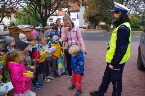 kobieta bierze cytrynę, obok policjantka i dzieci
