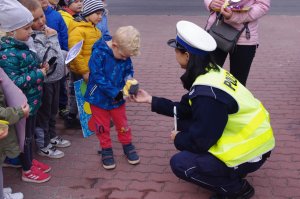 pochylona nad dzieckiem policjantka wręcza mu maskotkę