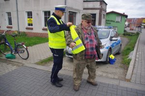 policjant drogówki ubiera kamizelkę odblaskową mężczyźnie