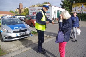 policjant wręcza kobiecie odblask w tel radiowóz