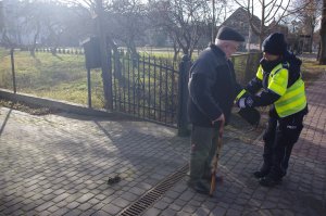 policjantka zakłada starszemu mężczyźnie opaskę odblaskowa