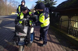 policjantka zakłada mężczyźnie na wózku inwalidzkim kamizelkę