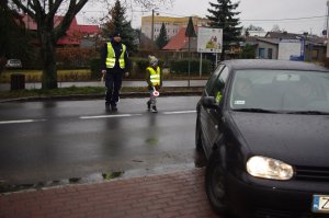 policjant i dziecko zatrzymują auto, w tle ulica