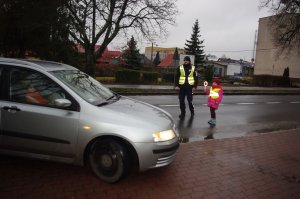policjant i dziecko zatrzymują auto, w tle ulica