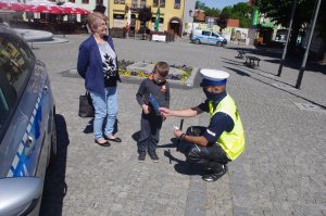 policjant wręcza dzieciom odblaski w tel radiowóz