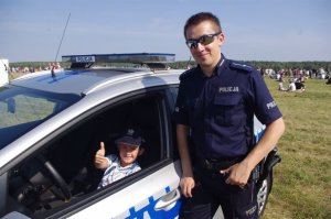 policjant,  w tle dziecko w radiowozie