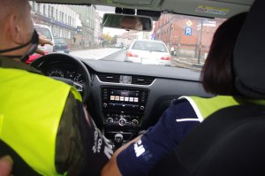mundurowi w radiowozie ŻW, policjantka zatrzymuje pojazd w tle ulica