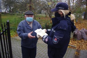 policjantka wręcza seniorowi ekologiczną torbę, w tle zarośla