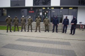 policjanci i żołnierze, w tle budynek komendy