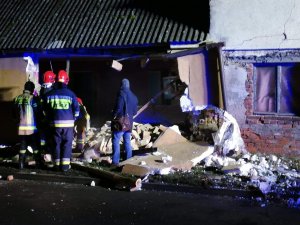 uszkodzony dom, przed nim strażacy i cywil
