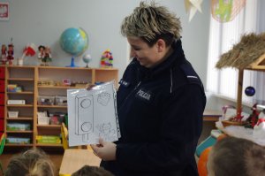 policjantka prezentuje ilustracje, w tle sala przedszkolna