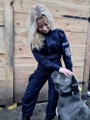 policjantka ze swoim psem, w tle ogrodzenie
